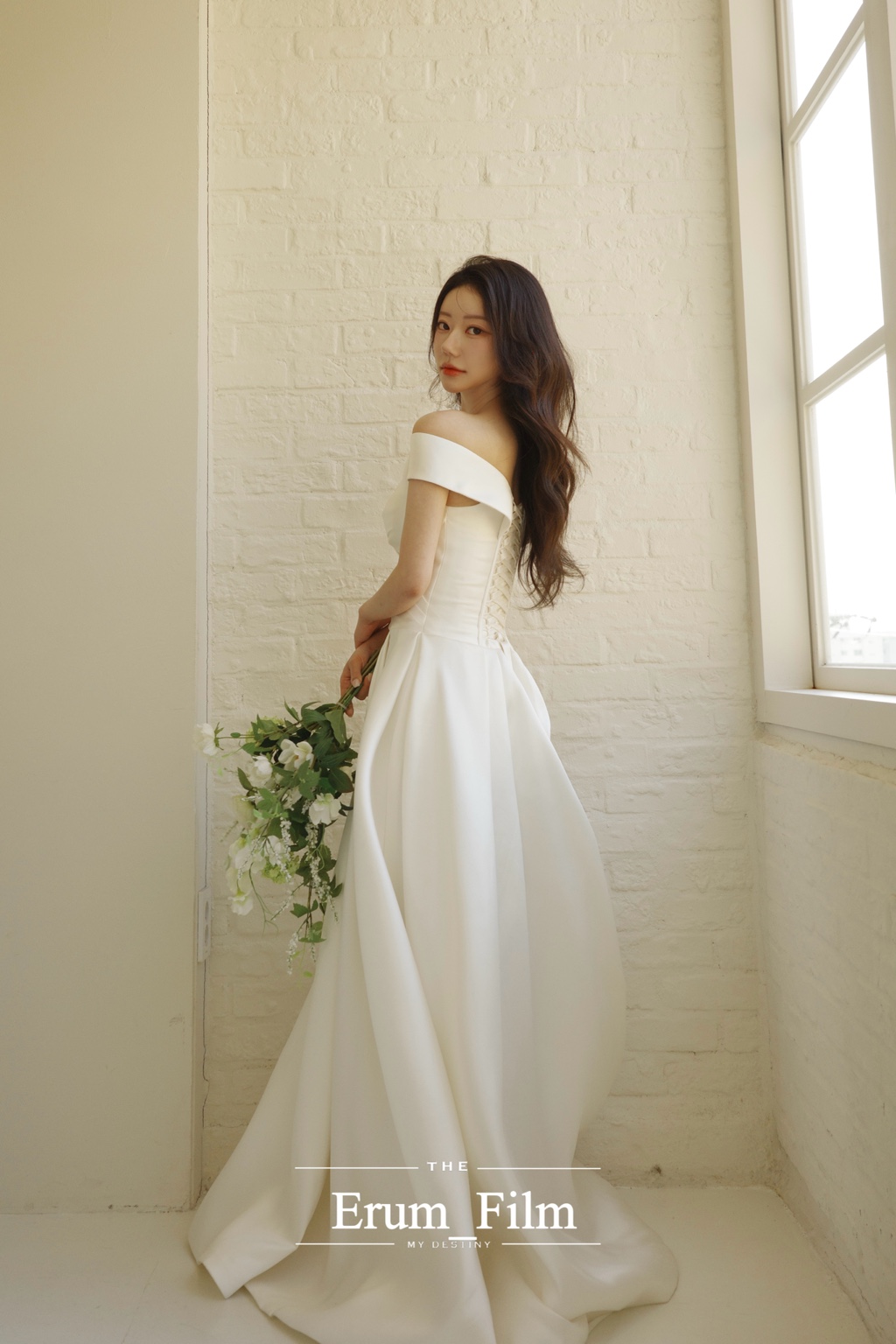 창가의 화이트 벽 앞에서 뒤를 돌아보는 신부