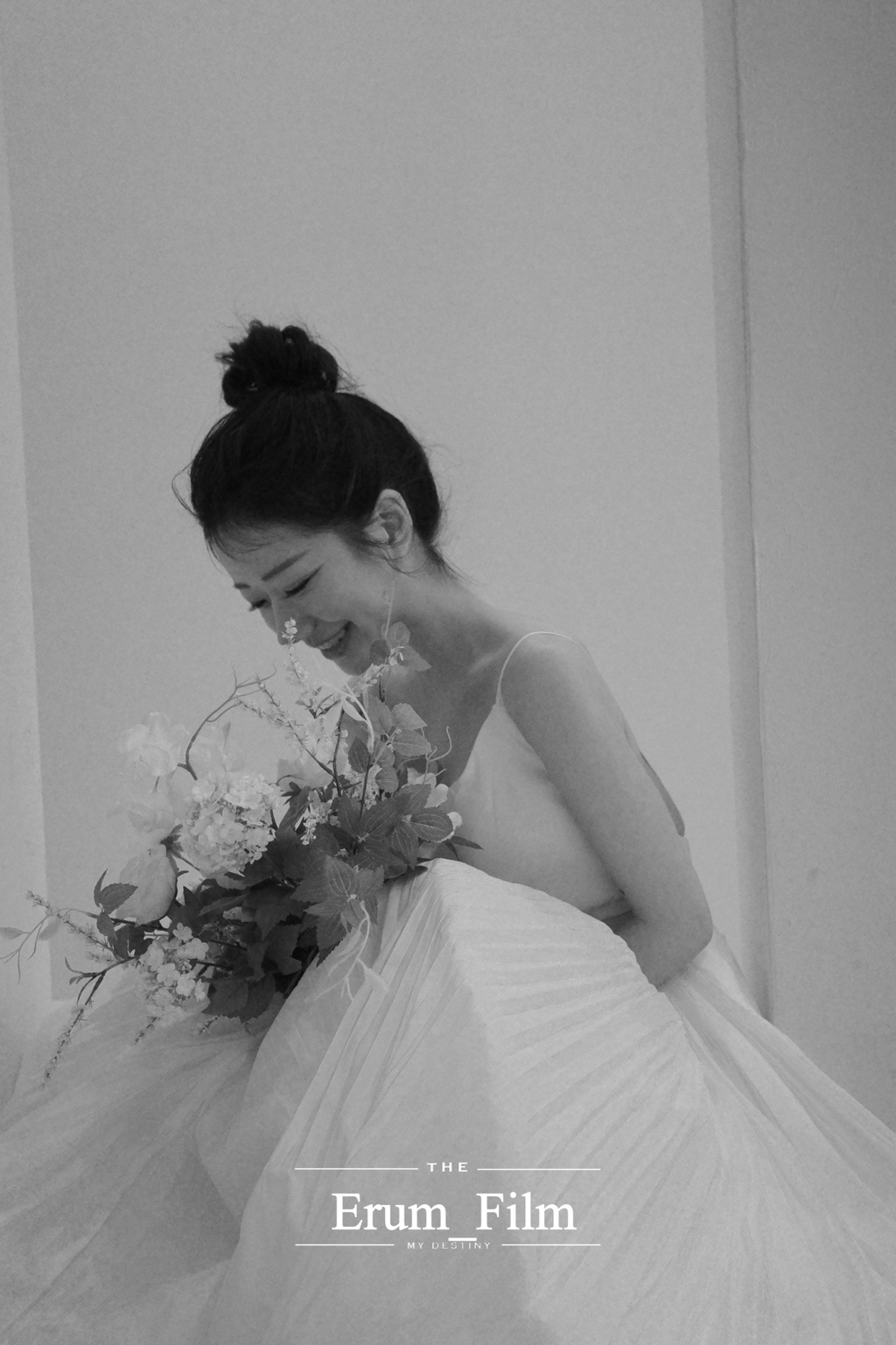 꽃다발을 안고 미소 짓는 신부의 흑백 사진