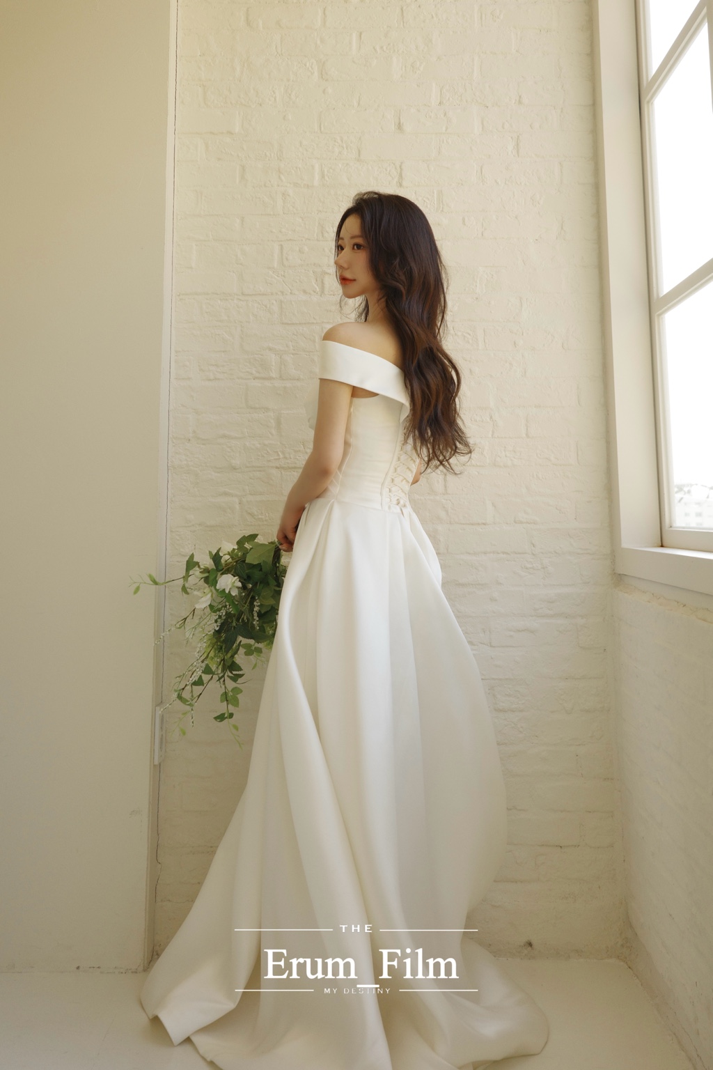 창가에서 드레스의 뒷모습을 보여주는 신부